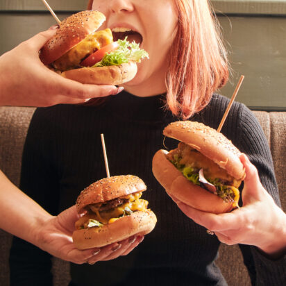 A girl with three burgers in front of her.