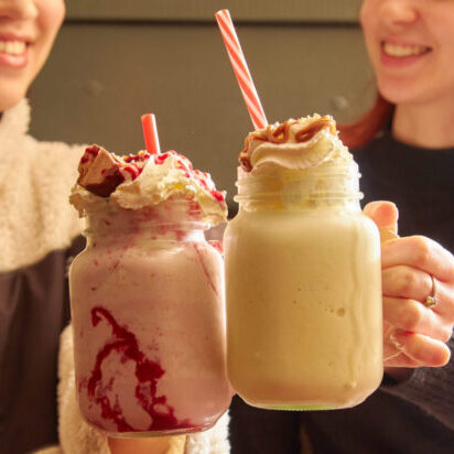 Two girls cheersing drinks.