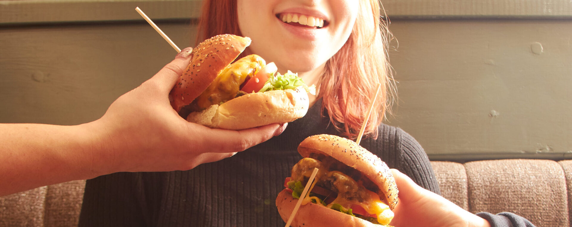 A girl with two burgers in front of her.
