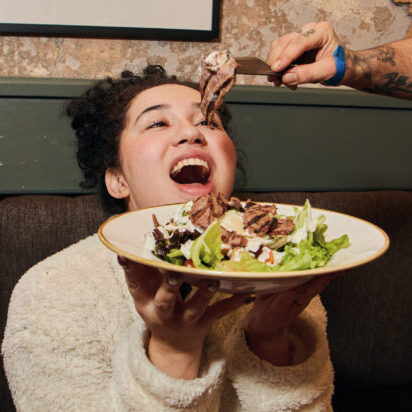 A girl having food hovering above her mouth.