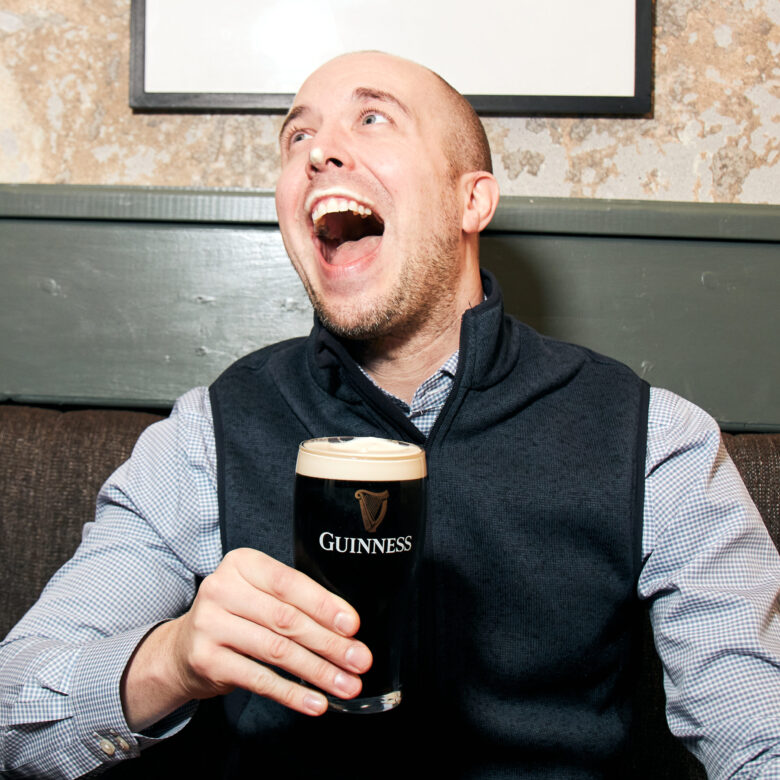 man laughing while holding a pint.