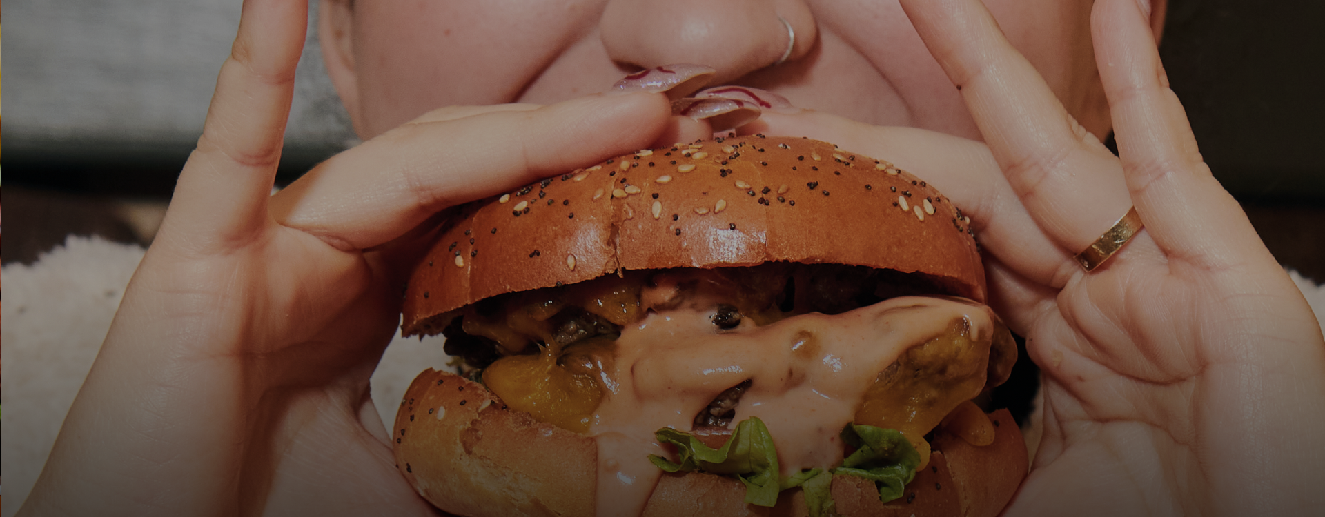 A close up shot of a girl eating a hamburger.