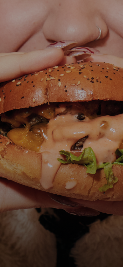 A close up shot of a girl eating a hamburger.