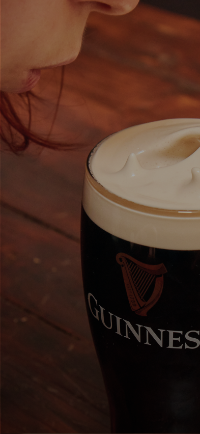 A girl blowing softly into her pint.