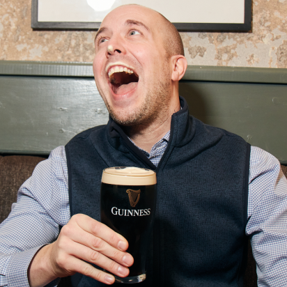 A man holding a pint smiling.